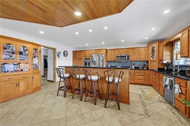 kitchen with light tile flooring, stainless steel appliances, backsplash, a kitchen bar, and a center island