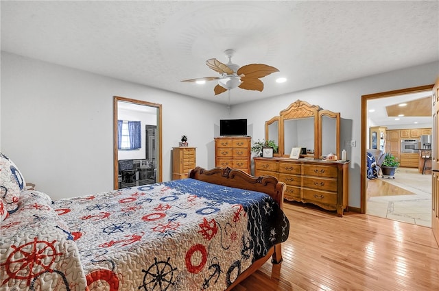 bedroom with ceiling fan, connected bathroom, a textured ceiling, and hardwood / wood-style flooring