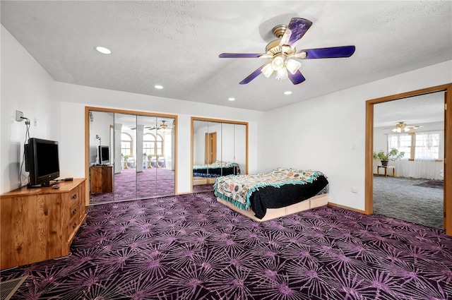 bedroom featuring french doors, two closets, dark colored carpet, a textured ceiling, and ceiling fan