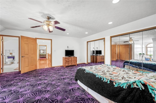 carpeted bedroom with two closets, ceiling fan, a textured ceiling, and lofted ceiling