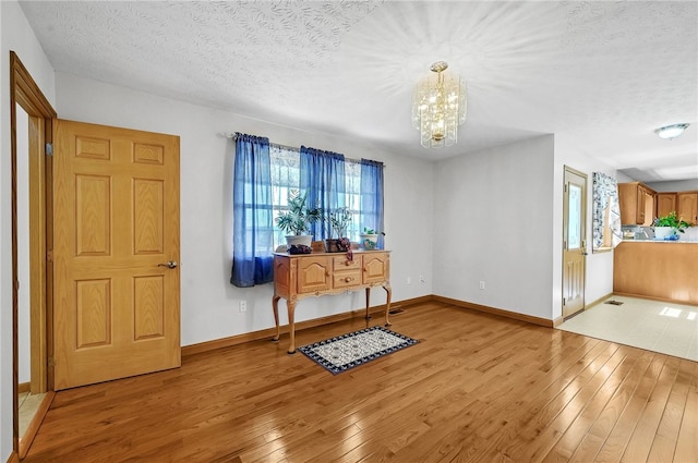 foyer featuring an inviting chandelier, a textured ceiling, and light tile floors