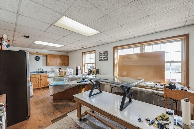 living room featuring light hardwood / wood-style floors, sink, and a drop ceiling