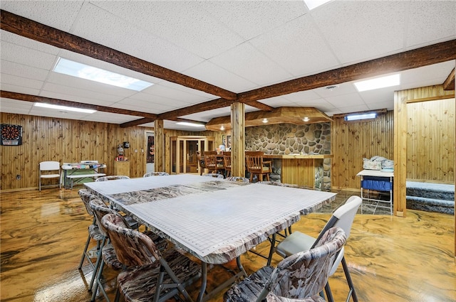 dining area featuring wood walls, hardwood / wood-style flooring, and a drop ceiling