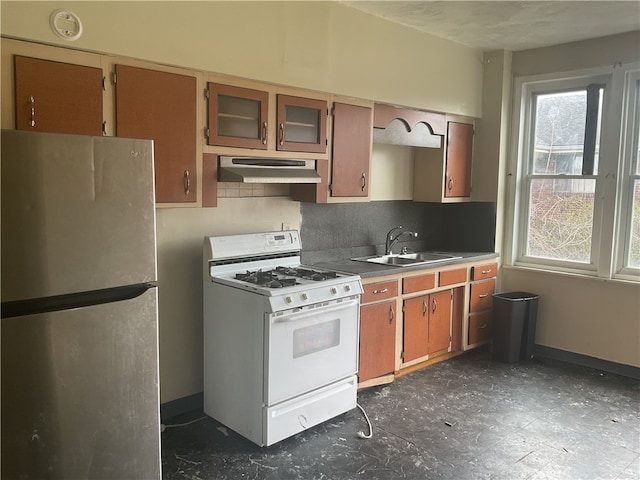 kitchen with dark tile floors, white range with gas stovetop, tasteful backsplash, stainless steel fridge, and fume extractor