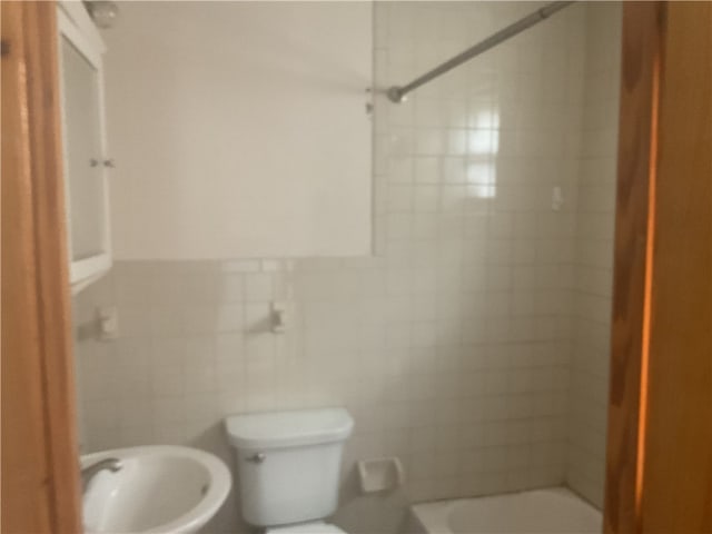 full bathroom with tile walls, sink, toilet, and tiled shower / bath combo