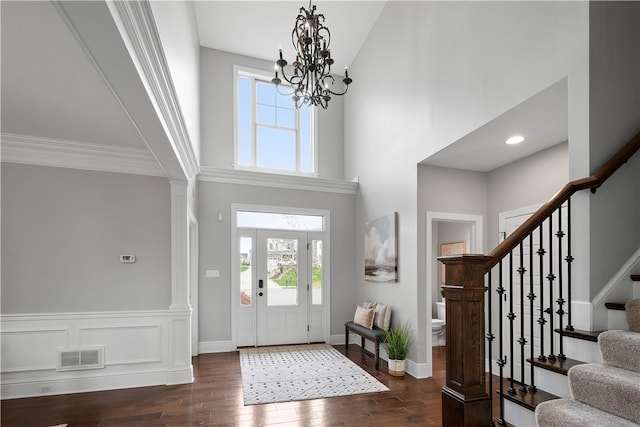 foyer featuring a towering ceiling, dark wood-type flooring, and a chandelier