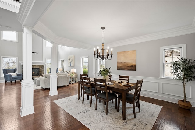 dining room featuring ornamental molding, dark wood-type flooring, decorative columns, and a notable chandelier