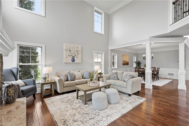 living room featuring a high ceiling, dark hardwood / wood-style floors, ornamental molding, a healthy amount of sunlight, and ornate columns