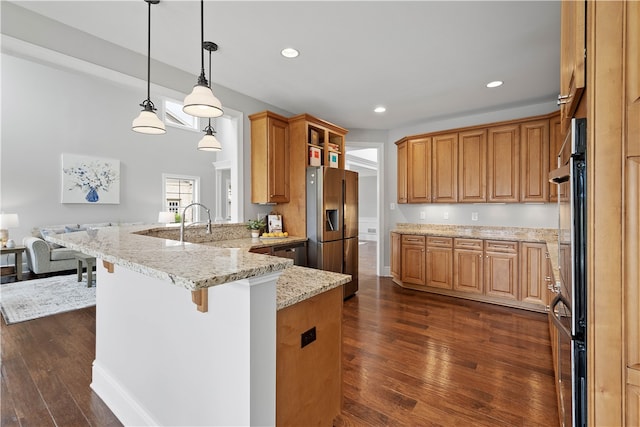 kitchen featuring pendant lighting, dark wood-type flooring, light stone countertops, and stainless steel fridge