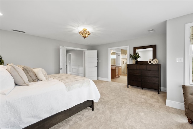 bedroom with ensuite bath and light carpet