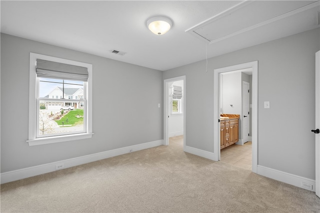 unfurnished bedroom featuring light colored carpet and connected bathroom