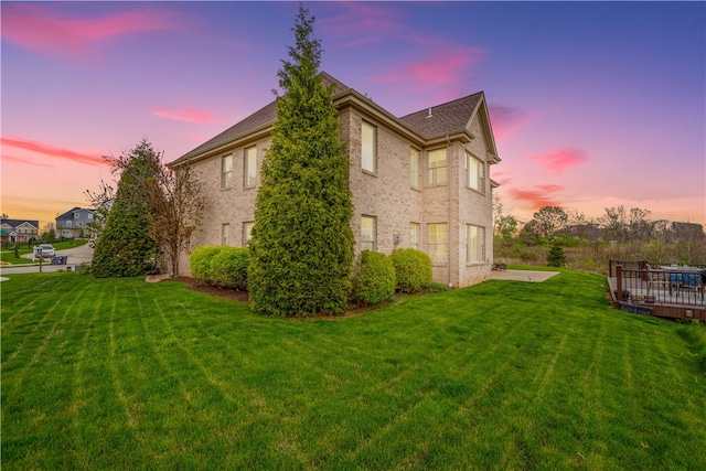 property exterior at dusk featuring a wooden deck and a lawn