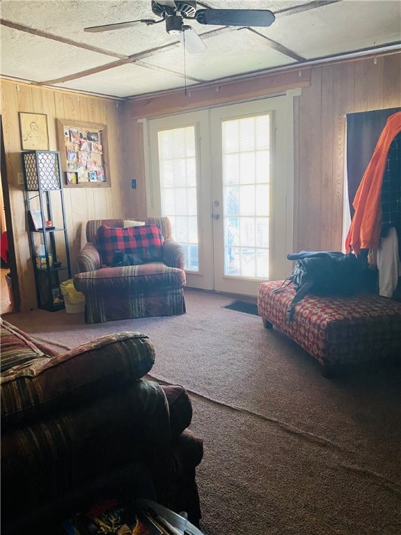 carpeted bedroom with french doors, wood walls, ceiling fan, and a textured ceiling