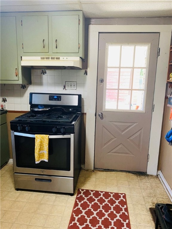 kitchen featuring custom range hood, backsplash, light tile floors, and stainless steel gas range oven