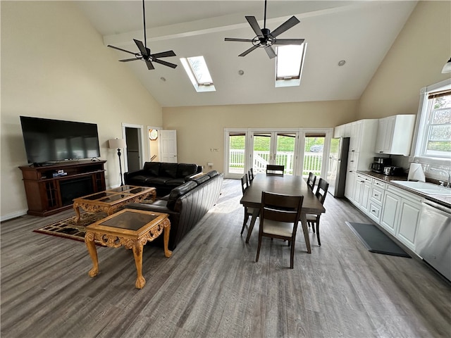 living room with a skylight, ceiling fan, high vaulted ceiling, and sink