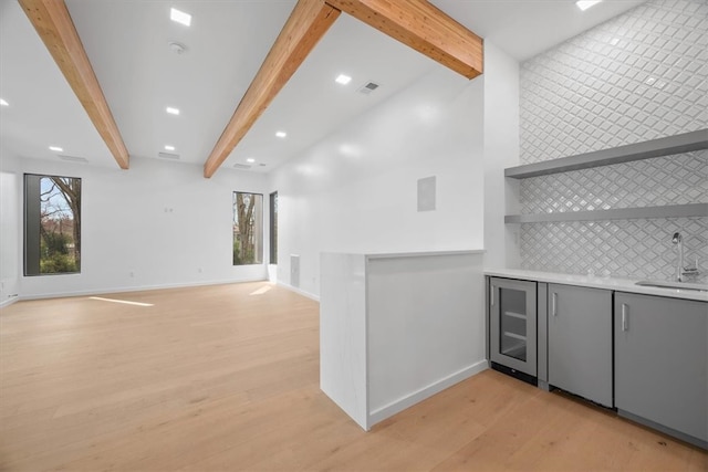 interior space with beam ceiling, light hardwood / wood-style floors, and wine cooler