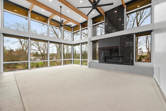 unfurnished living room featuring beamed ceiling, tile patterned flooring, a large fireplace, ceiling fan, and a towering ceiling