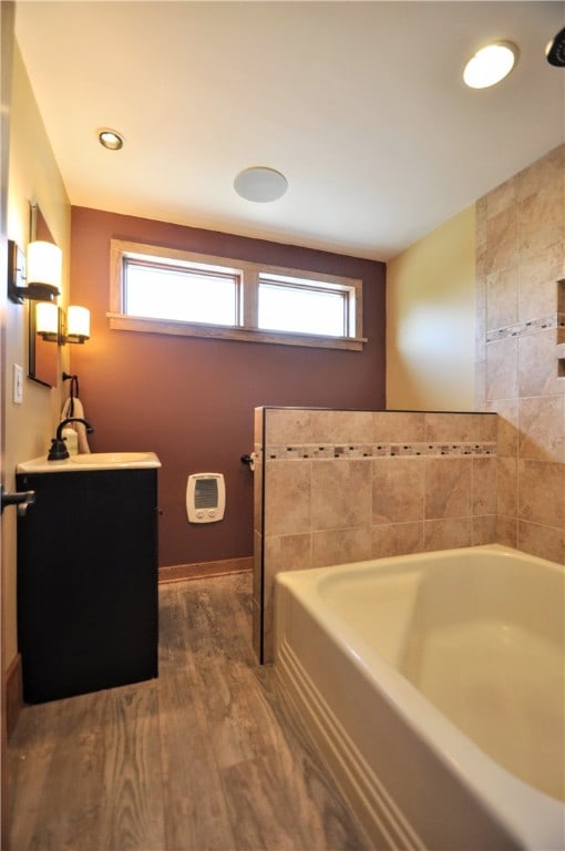 bathroom with hardwood / wood-style floors, a bath to relax in, and vanity