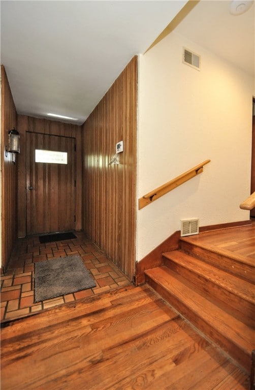 stairway with wooden walls and dark hardwood / wood-style floors