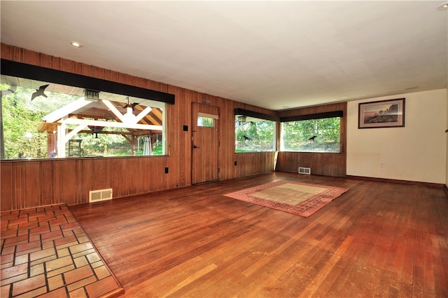 spare room featuring dark hardwood / wood-style flooring and wood walls