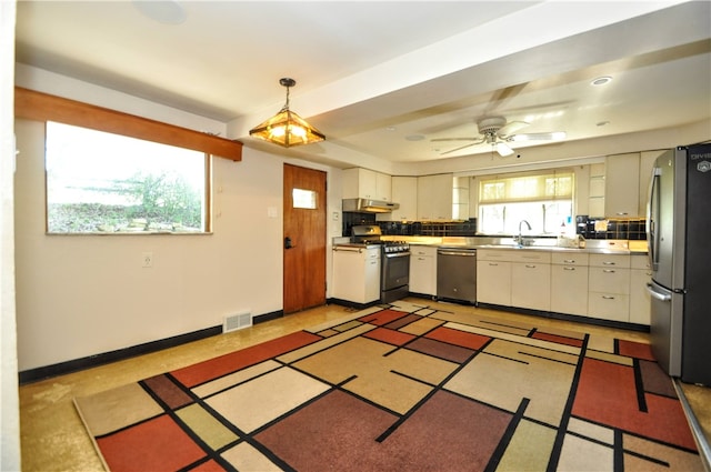 kitchen with ventilation hood, appliances with stainless steel finishes, backsplash, ceiling fan, and pendant lighting