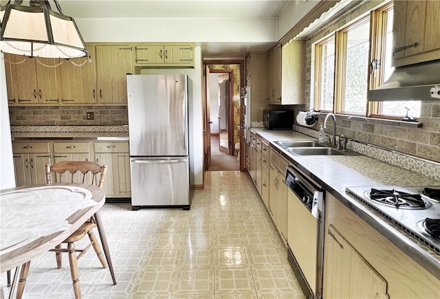 kitchen featuring sink, backsplash, dishwashing machine, decorative light fixtures, and stainless steel fridge