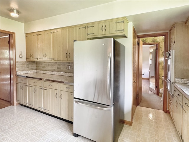 kitchen featuring backsplash, light brown cabinets, stainless steel fridge, and light tile flooring