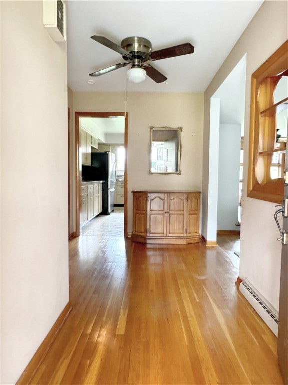 interior space with light hardwood / wood-style floors, ceiling fan, and a baseboard heating unit