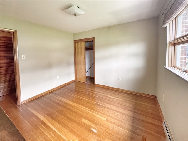 spare room featuring a baseboard radiator and light wood-type flooring