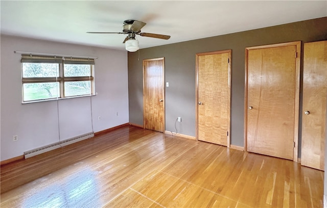 unfurnished bedroom with light hardwood / wood-style flooring, ceiling fan, a baseboard heating unit, and multiple closets