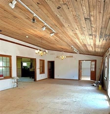 empty room with a chandelier, plenty of natural light, wooden ceiling, and vaulted ceiling