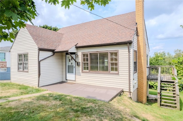 rear view of property featuring a wooden deck, a patio area, and a lawn