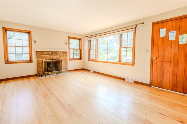 unfurnished living room featuring a stone fireplace and light hardwood / wood-style flooring