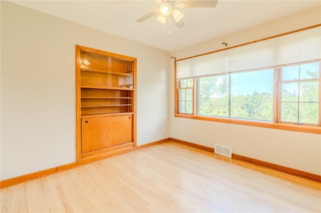 unfurnished room featuring ceiling fan, built in features, and hardwood / wood-style flooring