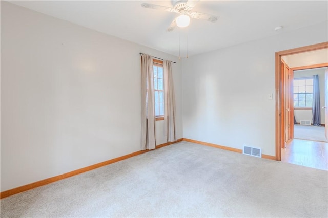 empty room with ceiling fan and light carpet