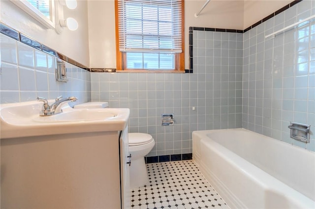 bathroom featuring tile patterned floors, vanity, toilet, and tile walls