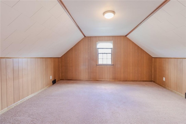 bonus room with light colored carpet and vaulted ceiling