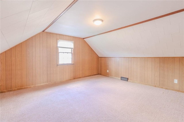 bonus room featuring light colored carpet, wooden walls, and vaulted ceiling