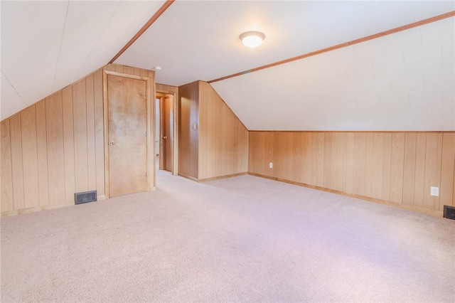 additional living space with light colored carpet, wooden walls, and vaulted ceiling