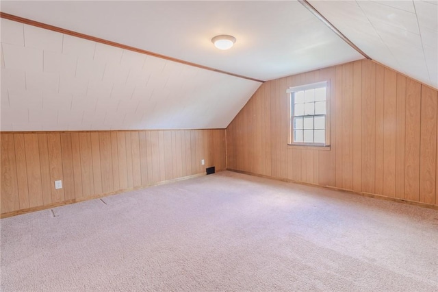 bonus room with wooden walls, light colored carpet, and lofted ceiling