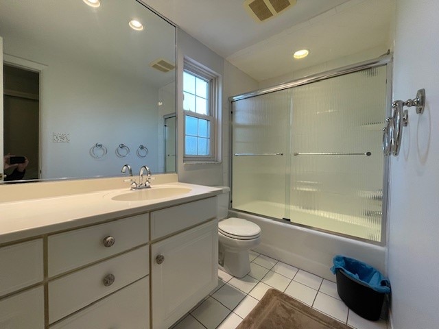 full bathroom with combined bath / shower with glass door, tile patterned floors, vanity, and toilet