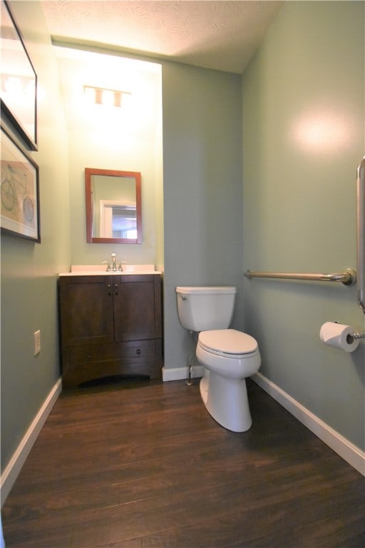 bathroom featuring wood-type flooring, a textured ceiling, vanity, and toilet