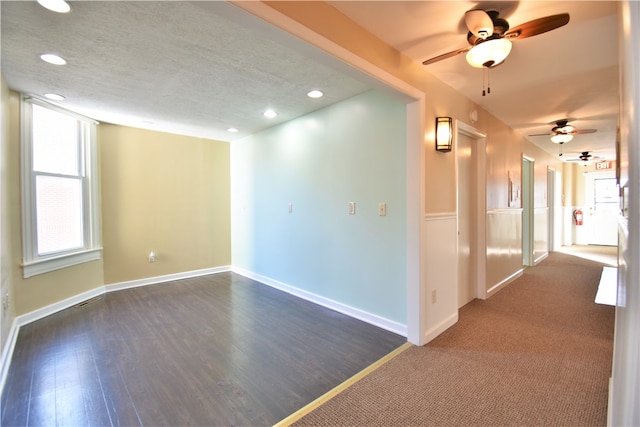 interior space with a textured ceiling, ceiling fan, and dark wood-type flooring