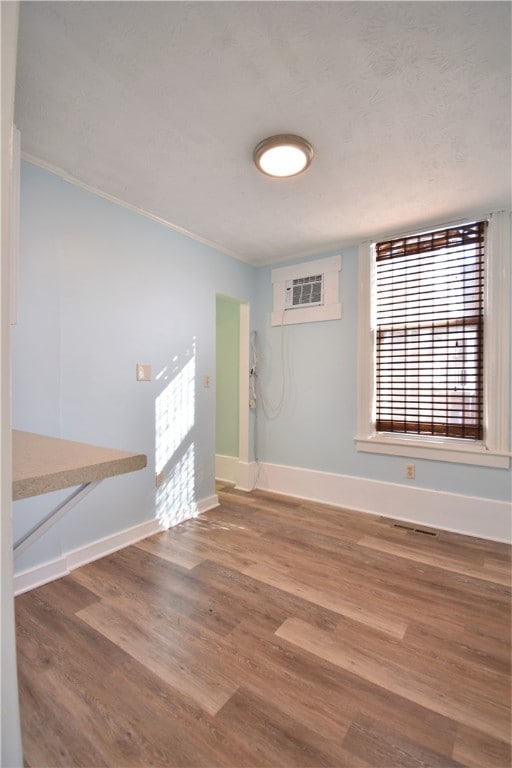 empty room featuring ornamental molding, wood-type flooring, and an AC wall unit