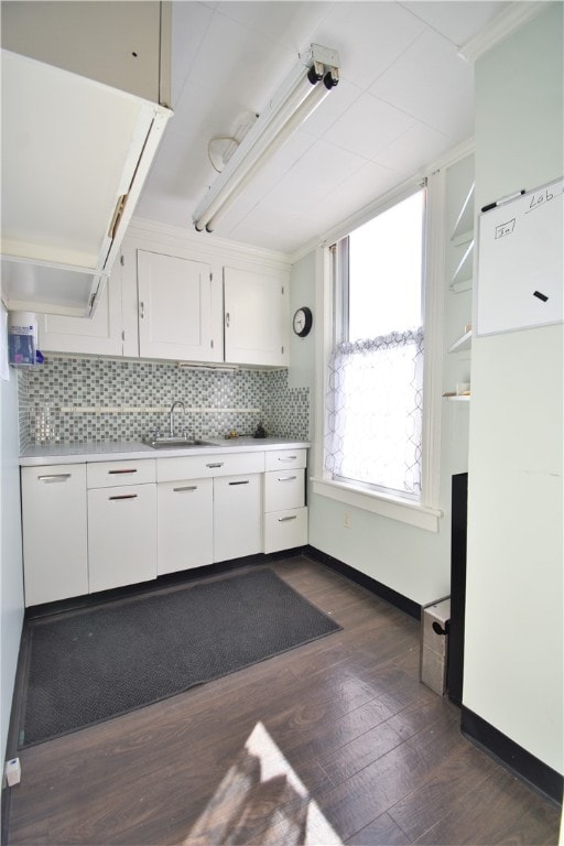 kitchen featuring white cabinets, sink, backsplash, dark hardwood / wood-style flooring, and ornamental molding