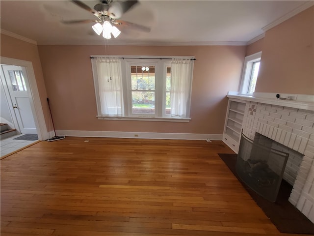 unfurnished living room with ceiling fan, ornamental molding, hardwood / wood-style floors, and a brick fireplace