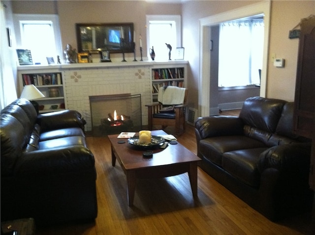 living room featuring a brick fireplace and hardwood / wood-style floors