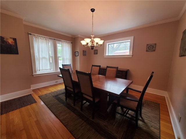 dining space with crown molding, an inviting chandelier, and light hardwood / wood-style flooring