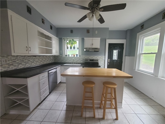 kitchen featuring backsplash, stainless steel appliances, a center island, white cabinets, and a kitchen bar