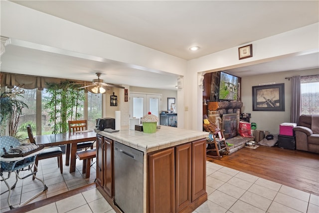 kitchen with french doors, stainless steel dishwasher, ceiling fan, light tile patterned floors, and tile countertops